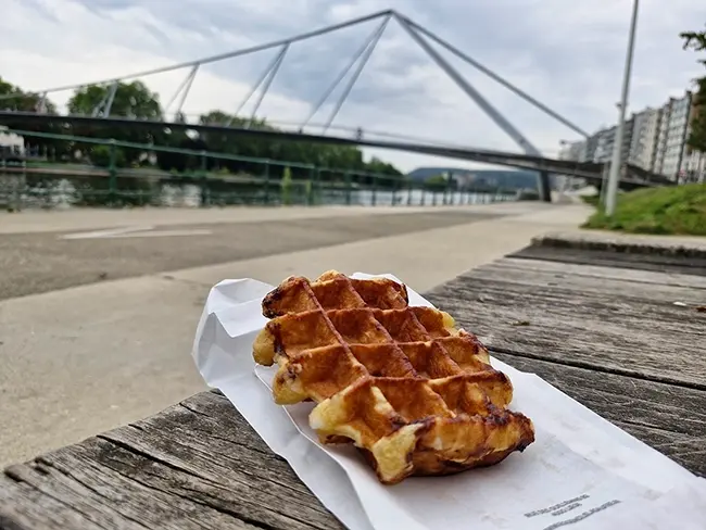 Dégustation d'une gaufre de Liège le long des quais face à la Meuse.