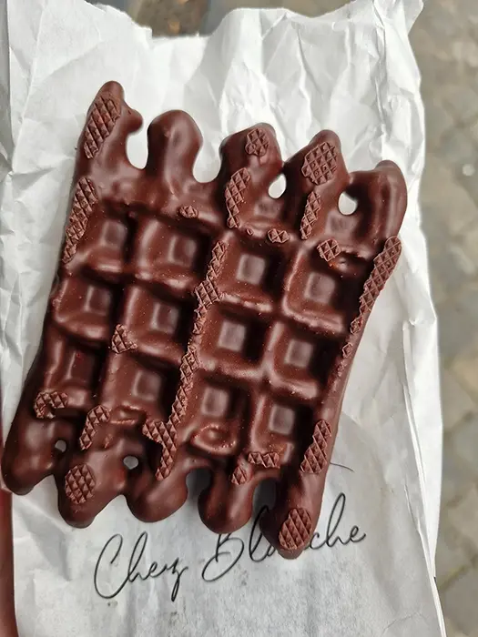 Dégustation d'une gaufre originale chocolatée dans la rue.